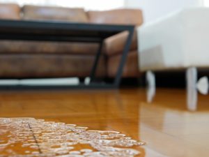 Close up of water flooding on living room parquet floor in a house – damage caused by water leakage