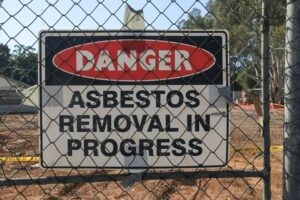 black, white and red Danger Asbestos Removal In Progress warning site on wire fence Commercial Asbestos Abatement SMART Environmental Services Kansas City AdobeStock_610211494