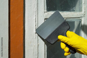 A professional in PPE scraping lead paint